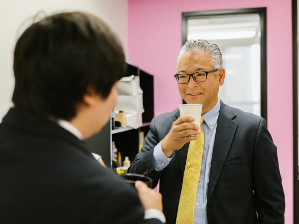 asian man talking to a colleague with tea
