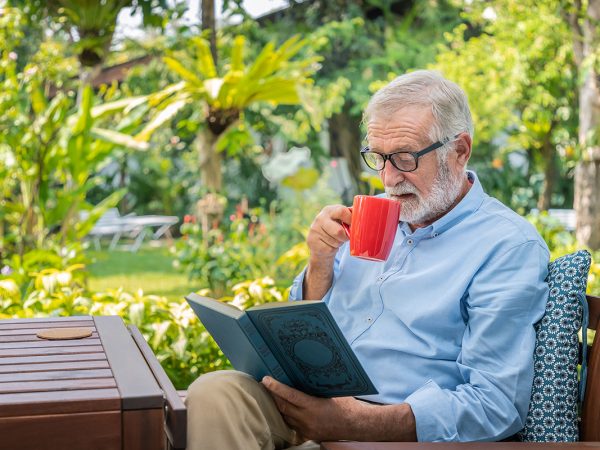 elderly man reading book and drinking tea